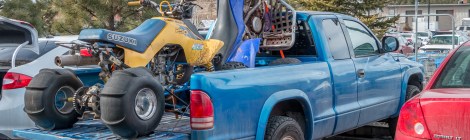 A pickup truck with two ATVs in its flatbed is in a parking space